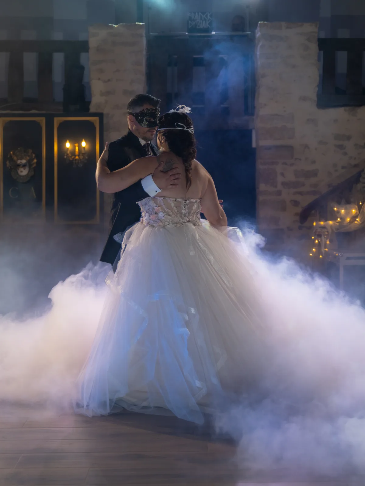 Première danse des mariés masqués dans la fumée, devant un décor noir et or