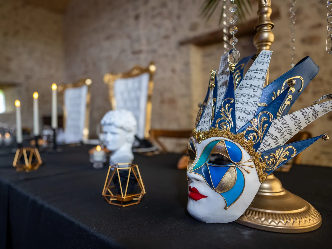 Masque d'arlequin orné de partitions de musique, posé sur la table d'honneur