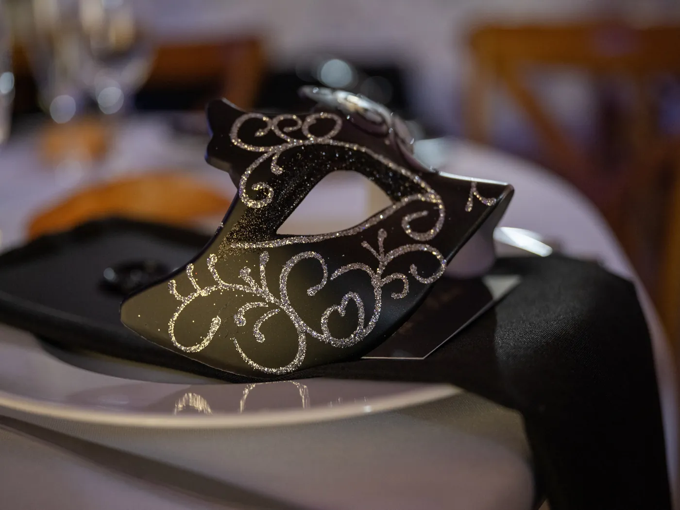 Masque noir pailleté d'argent posé sur une assiette