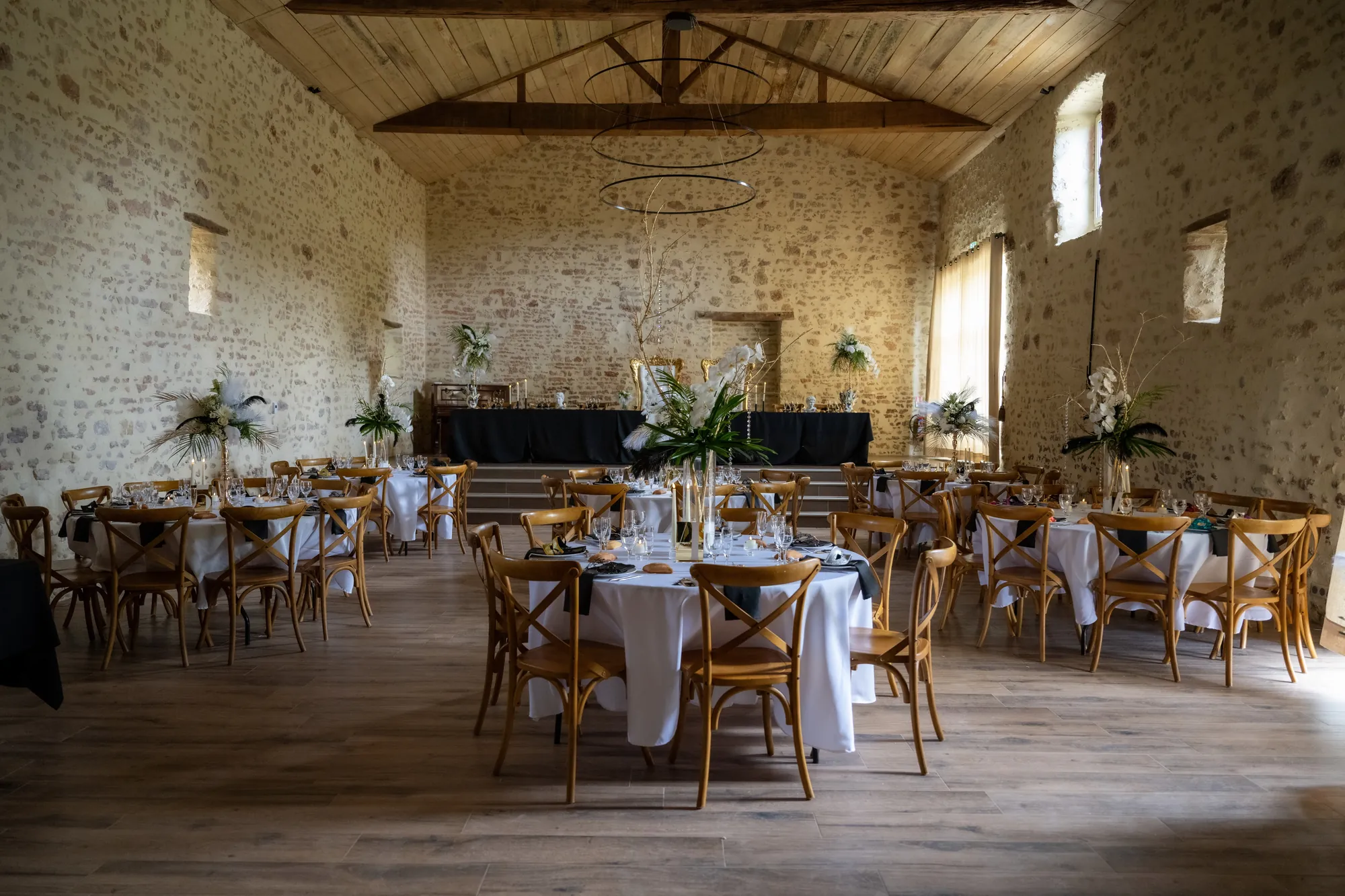 La salle de réception en pierre, avec ses tables rondes et ses centres de table à plumes